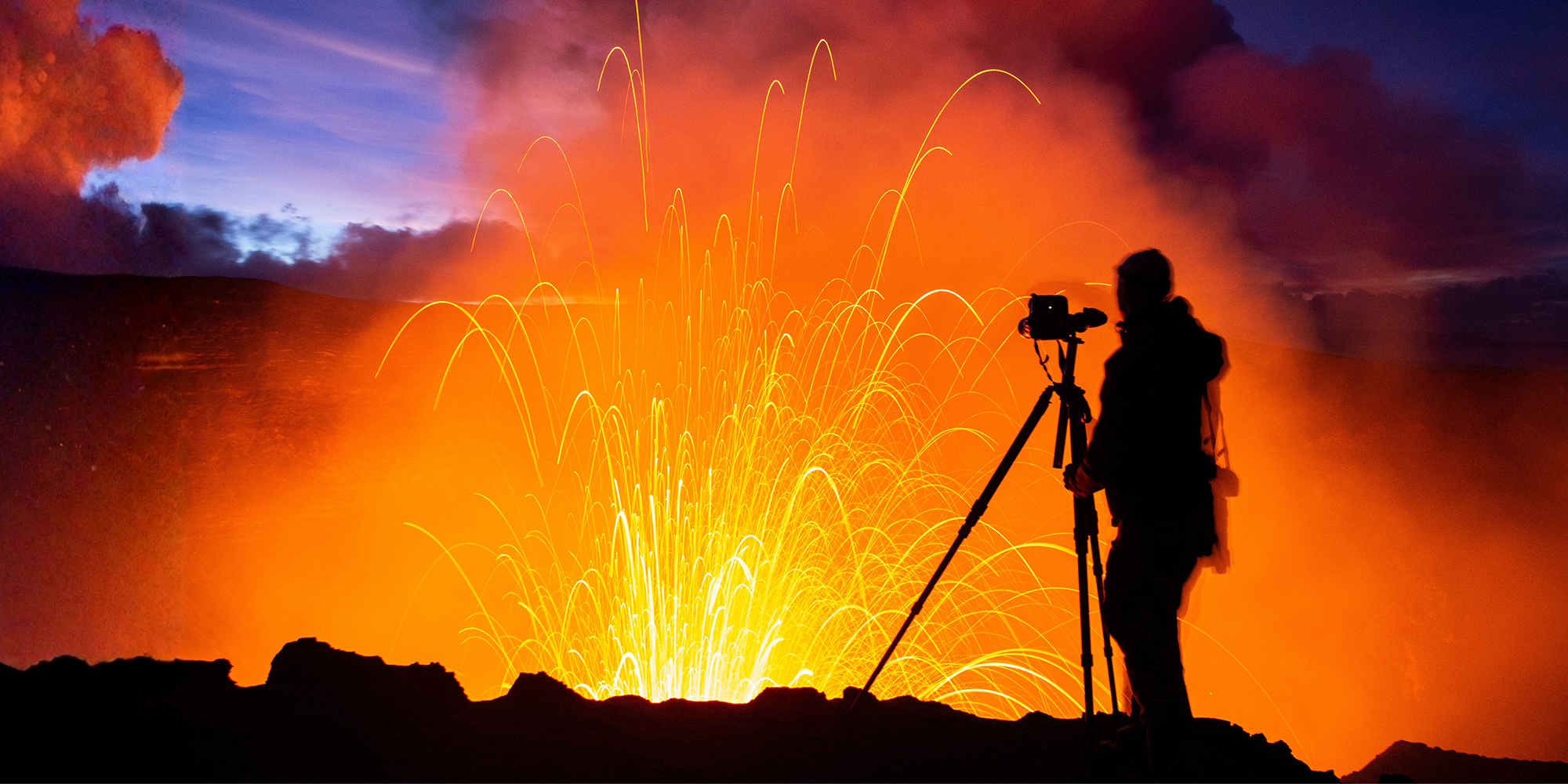 Photographer filming volcanic lava at night